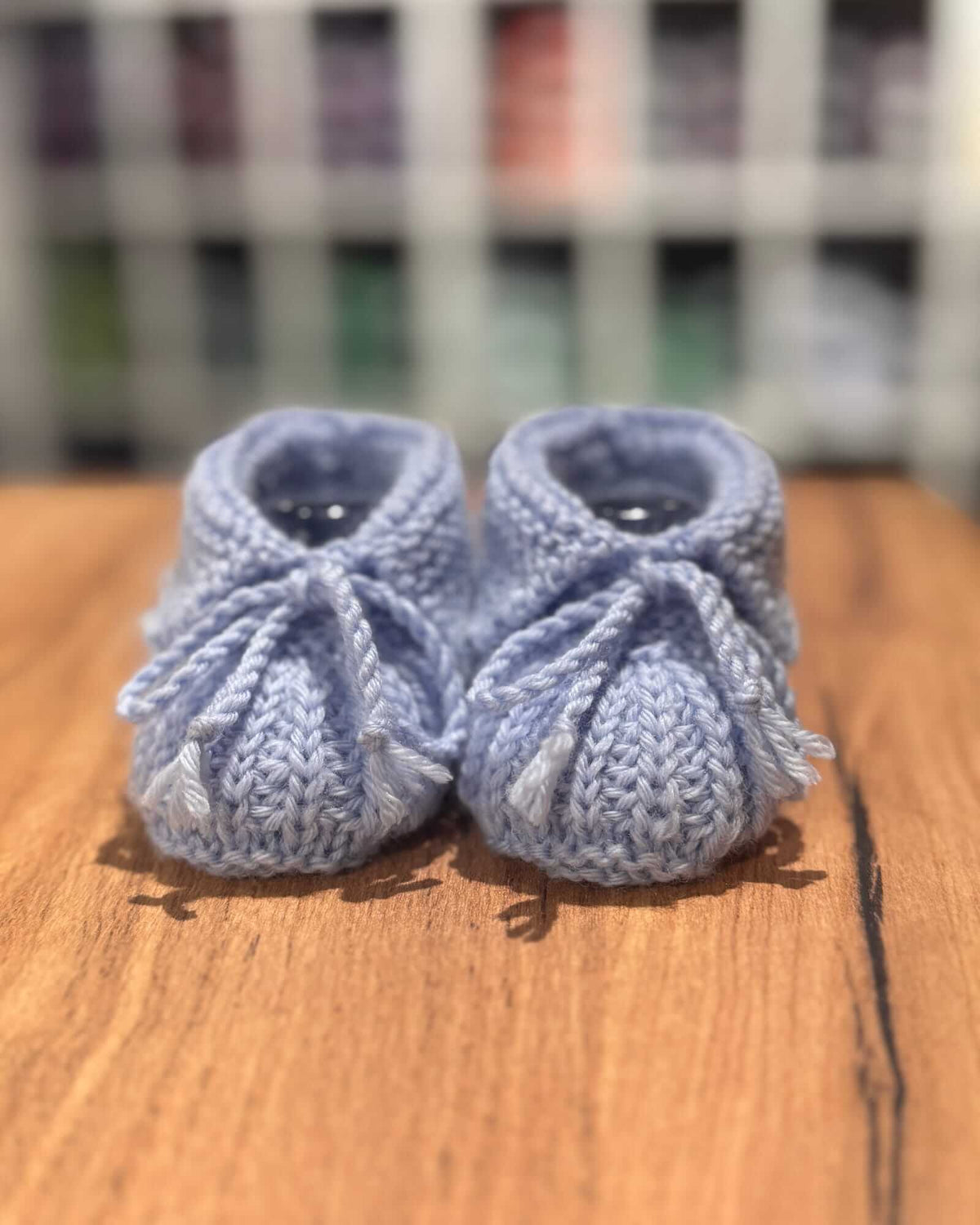 a close-up image of hand-knitted baby booties in light blue made of merino wool