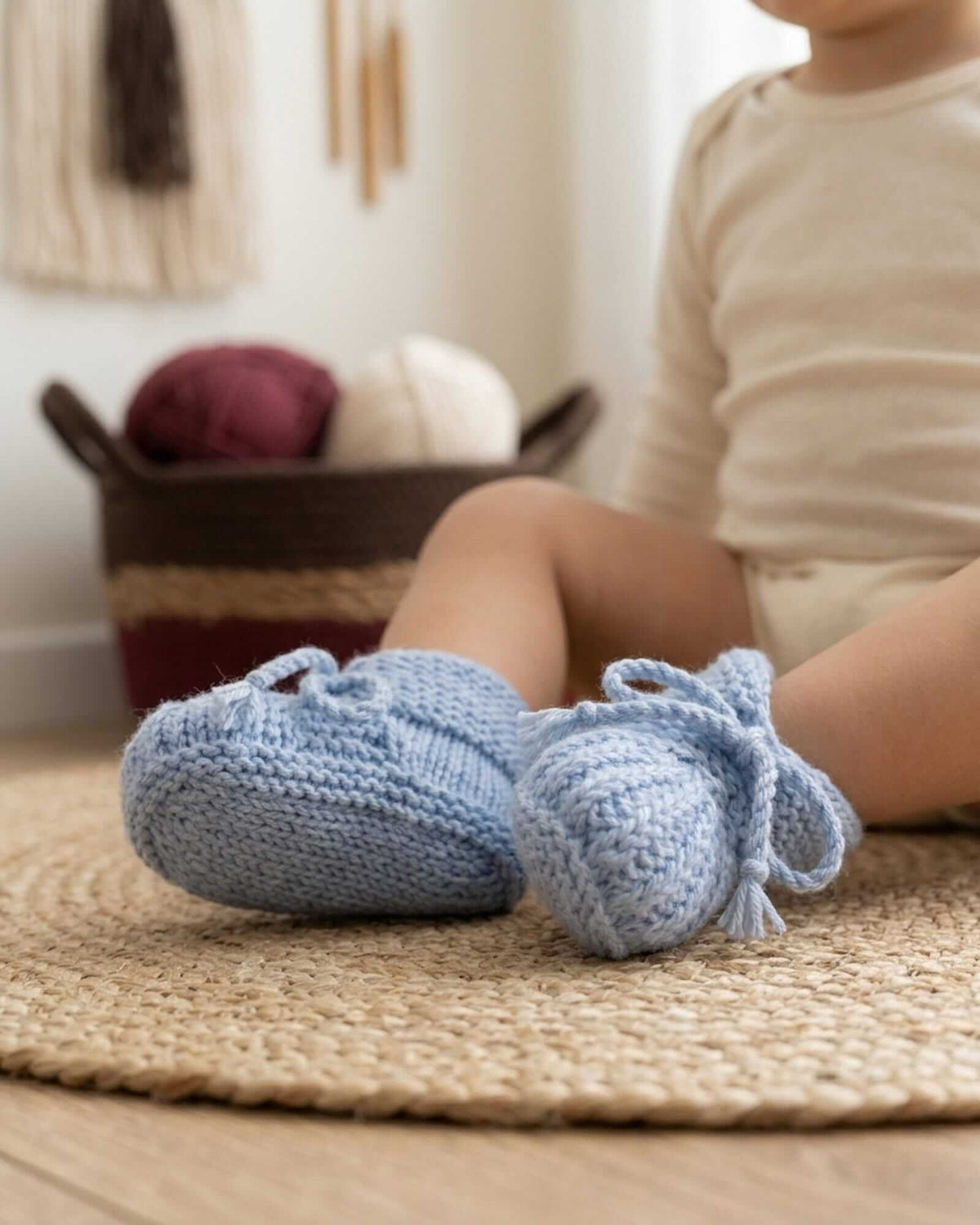 a close-up product image of a baby wearing hand-knitted baby booties in light blue made of merino wool