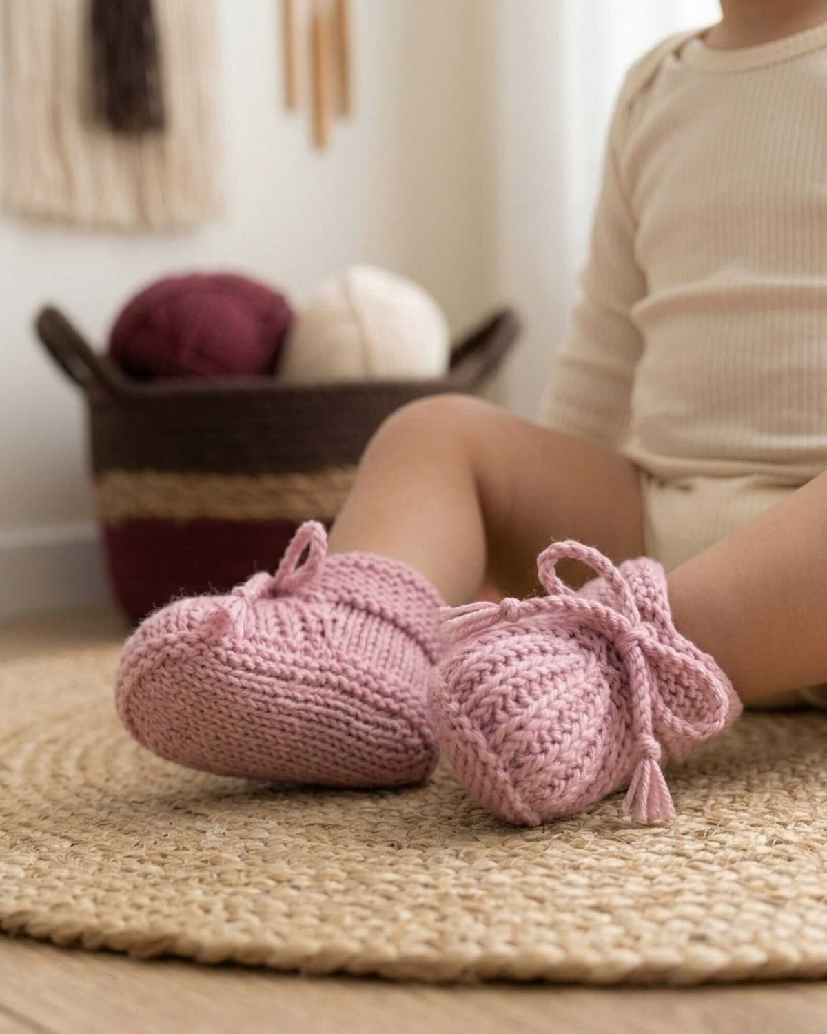 a close-up imagine of a baby wearing a pair of pink hand-knitted baby booties made of 100% merino wool